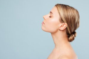Side profile view beautiful half naked topless young woman 20s with nude make up raise up head with close eyes isolated on plain pastel blue background Skin care healthcare cosmetic procedures concept